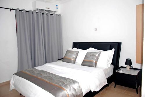 a bed with white sheets and pillows in a bedroom at The crown in Oyarifa