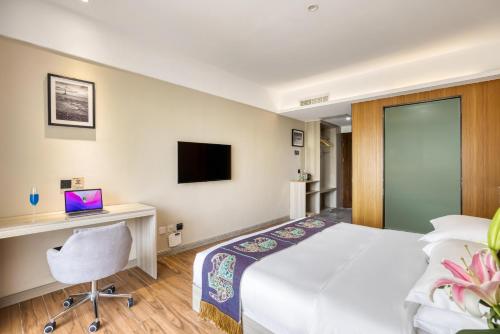 a hotel room with a bed and a desk and a computer at XiShuangBanNa Fanshe resort in Jinghong