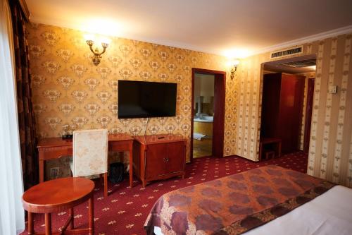 a hotel room with a bed and a desk and a television at Hotel La Castel Iasi in Iaşi