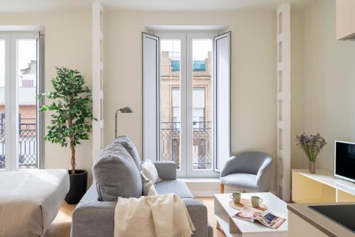 Una sala de estar con una cama, un sofá y sillas. en Ópera Apartments Alameda, en Sevilla
