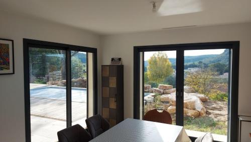 a dining room with a table and a large glass window at Provence, Uzès, villa climatisée 8 pers avec piscine privée in Gaujac