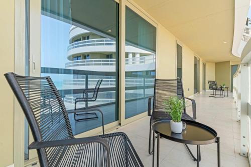 a balcony with two chairs and a table and a cruise ship at Silkhaus Vacation Homes Luxury 2BDR with Maid Room in Ajwan Towers in Abu Dhabi