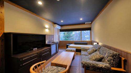a living room with a couch and a tv at Miyama Ouan Kyoritsu Resort in Takayama