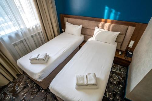 two beds in a hotel room with white towels at MILDOM Express in Almaty