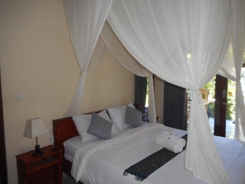 a bedroom with two beds with white drapes at Dika Homestay in Sidemen
