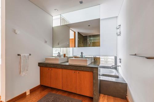 Un baño con dos lavabos y un espejo grande. en Sunny Villa, en Tróia