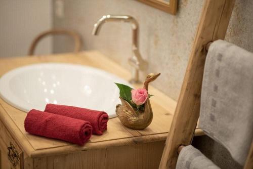 ein Waschbecken im Badezimmer mit einer Badewanne, auf der eine Blume prangt in der Unterkunft Nussbaum in Brixen