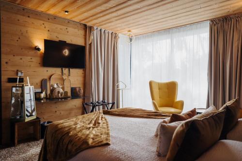 a bedroom with a bed and a chair and a window at Le Confidentiel Hôtel & SPA in Saint-Raphaël