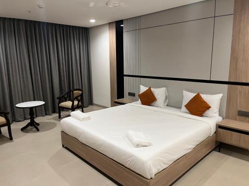 a bedroom with a large white bed with orange pillows at Hotel Shubham Celebrations-Miyapur in Lingampalli