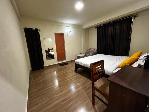 a bedroom with a bed and a desk and a table at Clouds Lodge in Cherrapunji