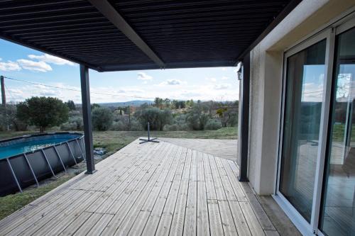 une terrasse en bois avec vue sur la piscine dans l'établissement Villa Amandine, à La Verdière