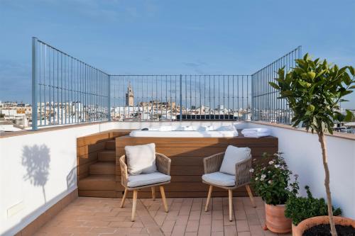 een balkon met een hot tub en 2 stoelen bij Magno Apartments Almansa in Sevilla