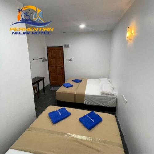 two beds in a small room with blue pillows at Perhentian Najmi Hotel in Perhentian Island