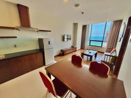 a kitchen and living room with a table and a refrigerator at Avatar Danang Hotel in Da Nang