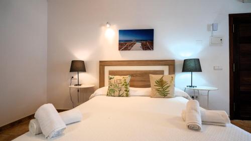 a bedroom with a large white bed with two lamps at Apartamentos Es Pou - Emar Hotels in Sant Ferran de Ses Roques