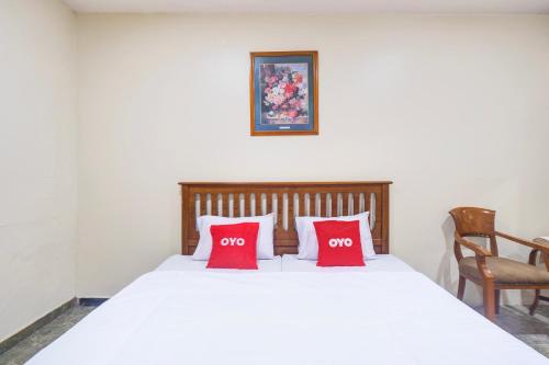 a bedroom with a white bed with two red pillows at Hotel O Bogor Near Museum Peta in Bogor