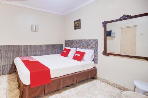 a bedroom with a bed with red pillows and a mirror at Hotel O Bogor Near Museum Peta in Bogor