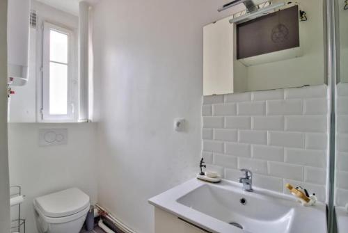 une salle de bain blanche avec des toilettes et un lavabo dans l'établissement Nice Flat Jules Joffrin station and Clignancourt, à Paris