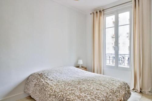 une chambre blanche avec un lit et une fenêtre dans l'établissement Nice Flat Jules Joffrin station and Clignancourt, à Paris