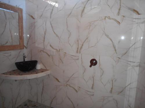 a white marble bathroom with a sink and a mirror at Dika Homestay in Sidemen