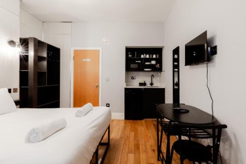 a bedroom with a bed and a table and a kitchen at Britannia Hyde Park Hotel by PLI in London