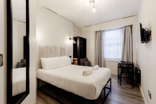 a bedroom with a bed and a desk and a window at Britannia Hyde Park Hotel in London