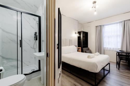 a small bedroom with a bed and a shower at Britannia Hyde Park Hotel in London