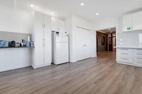 an empty kitchen with white cabinets and a hard wood floor at Stay at Swans in Darley