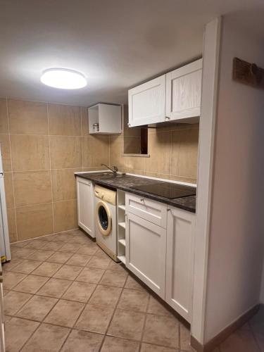 Una cocina con gabinetes blancos y lavadora y secadora. en Il Balconcino, en Gaeta