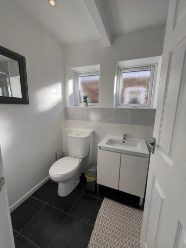 a white bathroom with a toilet and a sink at Chalet 149 Florida Holiday Park Hemsby in Hemsby