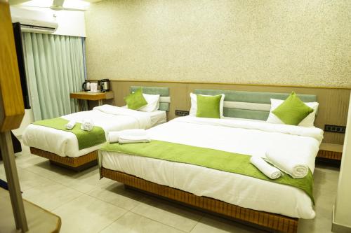 a hotel room with two beds with green pillows at Hotel city inn in Ahmedabad