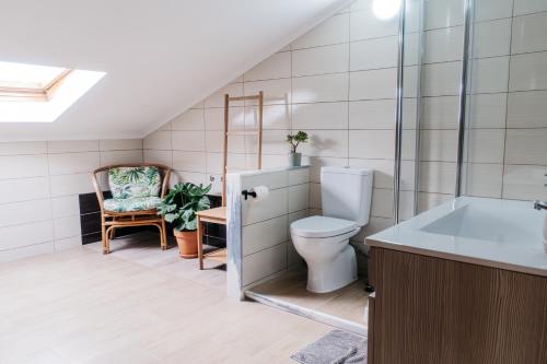 a bathroom with a toilet and a chair at Green House in Baleal