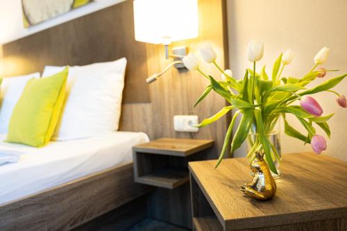 a bedroom with a bed and a vase of flowers on a table at Hotel Aulmann in Trier