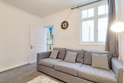 a living room with a gray couch and a window at Spacious 4 Bedroom Home - Sleeps Up to 9 Guests in Chelmsford