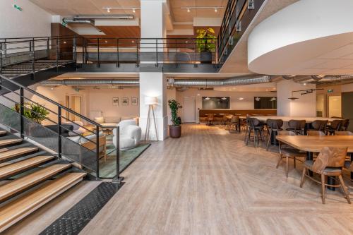 une grande chambre avec des tables, des chaises et des escaliers dans l'établissement Canvas La Défense, à Puteaux