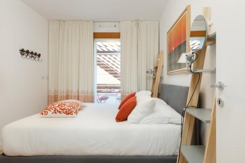 a bedroom with a bed with white sheets and orange pillows at Portopiccolo Apartments - Telgatino nel Golfo in Sistiana