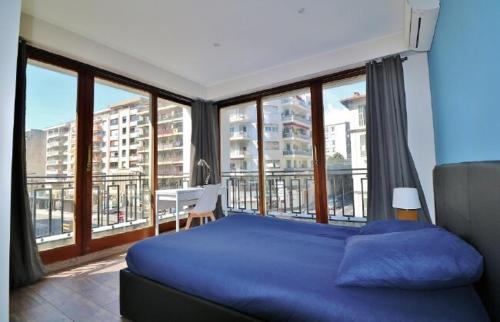 une chambre avec un lit bleu et une grande fenêtre dans l'établissement 3 pièces 55m2 - 30 m de la mer, à Nice