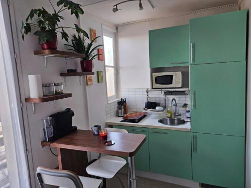 une petite cuisine avec des placards verts et une table en bois dans l'établissement Studio centre ville-Proche Paris, à Villejuif