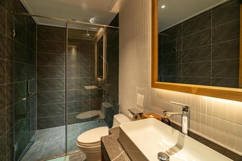 a bathroom with a toilet and a sink and a shower at Nam Dat Hotel by D'Lecia Ha Long in Ha Long