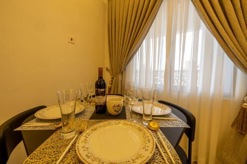 a table with plates and glasses and a bottle of wine at Caros Villa in Adentan