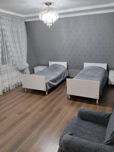 a bedroom with two beds and a couch and a chandelier at White cute house in Karakol