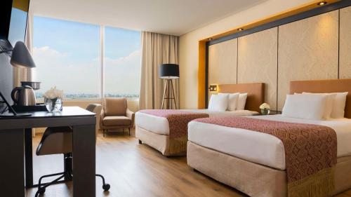 a hotel room with two beds and a desk at NH Collection Mexico City Airport T2 in Mexico City
