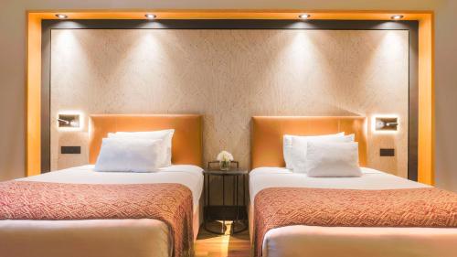 a hotel room with two beds and a mirror at NH Collection Mexico City Airport T2 in Mexico City