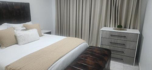 a bedroom with a bed and a dresser at Hungwe Apartment in Harare