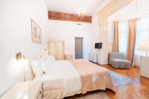a white bedroom with a large bed and a chair at Vila Camelia in Sinaia