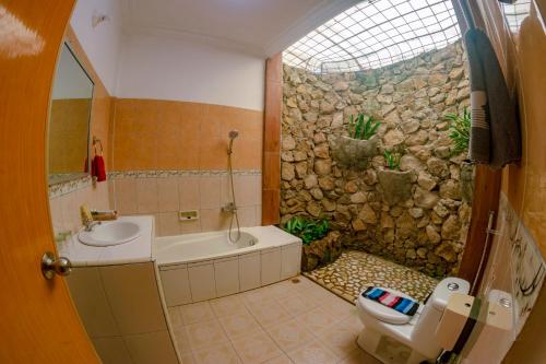 baño con lavabo, aseo y pared de piedra en Tabo Cottages, en Tuk Tuk