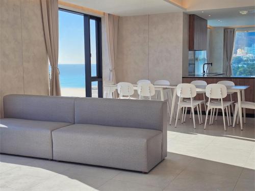 a living room with a couch and a table and chairs at 펜톤나인 해변열차 송정2호점 in Busan