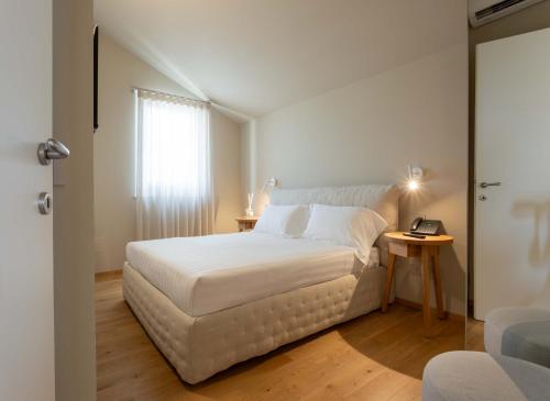 a bedroom with a white bed and a table at Relais La Colombaia in Appignano