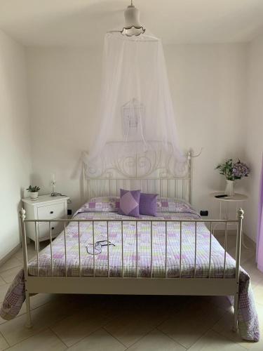a bedroom with a white bed with purple pillows at Le Rocce in SantʼAgata deʼ Goti