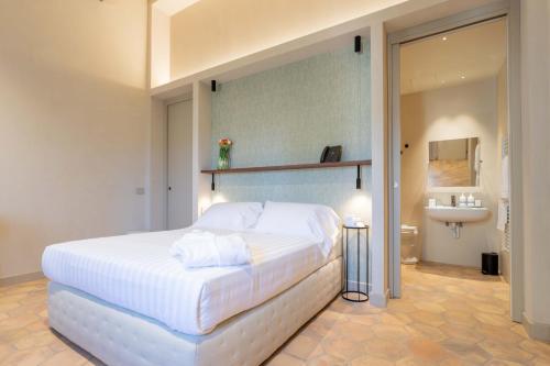 a bedroom with a large white bed and a sink at Relais La Colombaia in Appignano